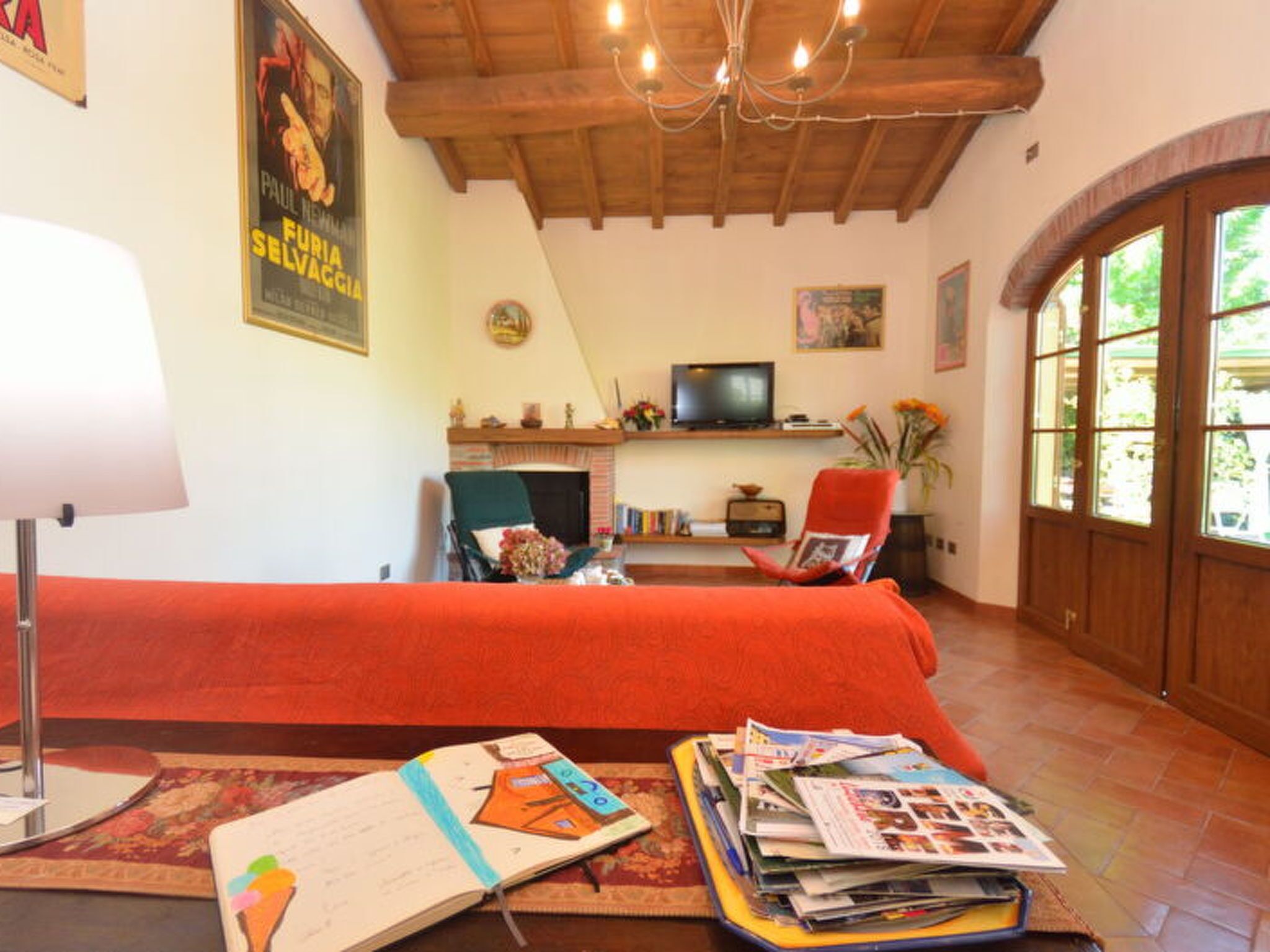 Uma sala de estar com um sofá vermelho, televisão, lareira e uma janela grande.