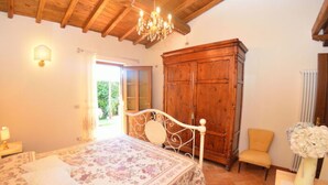 Una camera da letto con un letto, un'armadio in legno, una sedia e un lampadario.