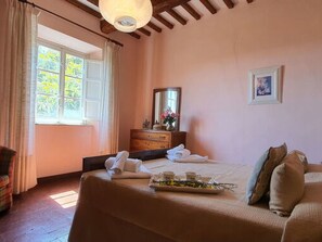 Ein Schlafzimmer mit Bett, Kommode, Spiegel und Fenster.