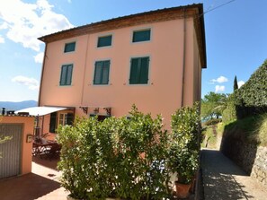 Un bâtiment à deux étages, doté d’un toit plat, de nombreuses fenêtres avec volets et d’un patio aménagé avec du mobilier d’extérieur.