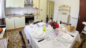 A dining area with a table set for four, kitchen cabinets, a stove, and a wine rack. - Alla Collina Del Sole by Interhome (Ciciana)