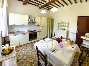 A kitchen with a dining table set for two, a refrigerator, and a microwave. - Alla Collina Del Sole by Interhome (Ciciana)