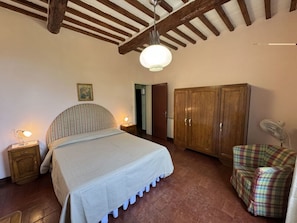 A bedroom with a bed, wooden wardrobe, a chair, a bedside table, and a ceiling fan. - Alla Collina Del Sole by Interhome (Ciciana)