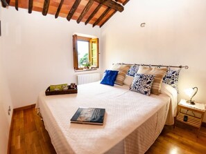 Ein Schlafzimmer mit einem Bett, einem Fenster, einem Nachttisch und einem Beistelltisch.