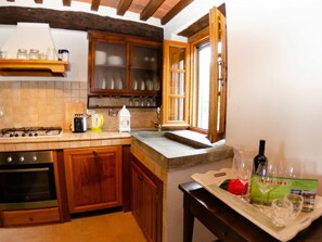 Eine Küche mit Holzausstattung, einem Gasherd, einem Backofen, einem Fenster und einem Tisch mit einer Flasche und Gläsern.