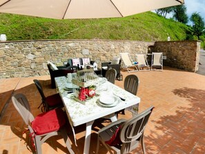 Eine Terrasse im Freien mit einer Steinmauer, einem Esstisch und Stühlen.