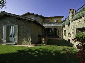 Ein Steinhaus mit gelber Fassade, einer Tür mit Fensterläden und einem kleinen Garten.