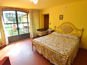 Ein Schlafzimmer mit Bett, Schreibtisch, Stuhl und Blick durch ein Fenster.