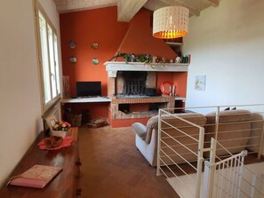 A room with a fireplace, a desk with a computer, a bunk bed, and a hanging light fixture. - Podere San Martino by Interhome (Buti)