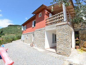 A two-story house with a stone facade, a balcony, and a gravel driveway. - Podere San Martino by Interhome (Buti)