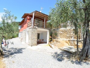 A two-story house with a stone facade, a balcony, and a gravel driveway. - Podere San Martino by Interhome (Buti)