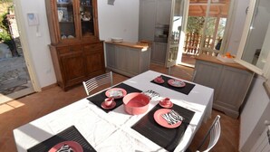 Un comedor con una mesa dispuesta para cuatro, un armario de madera con puertas de cristal y vistas al exterior.