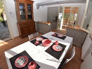 Ein Essbereich mit Tisch für vier Personen, einer Holzkabine mit Glastüren und Blick ins Freie.