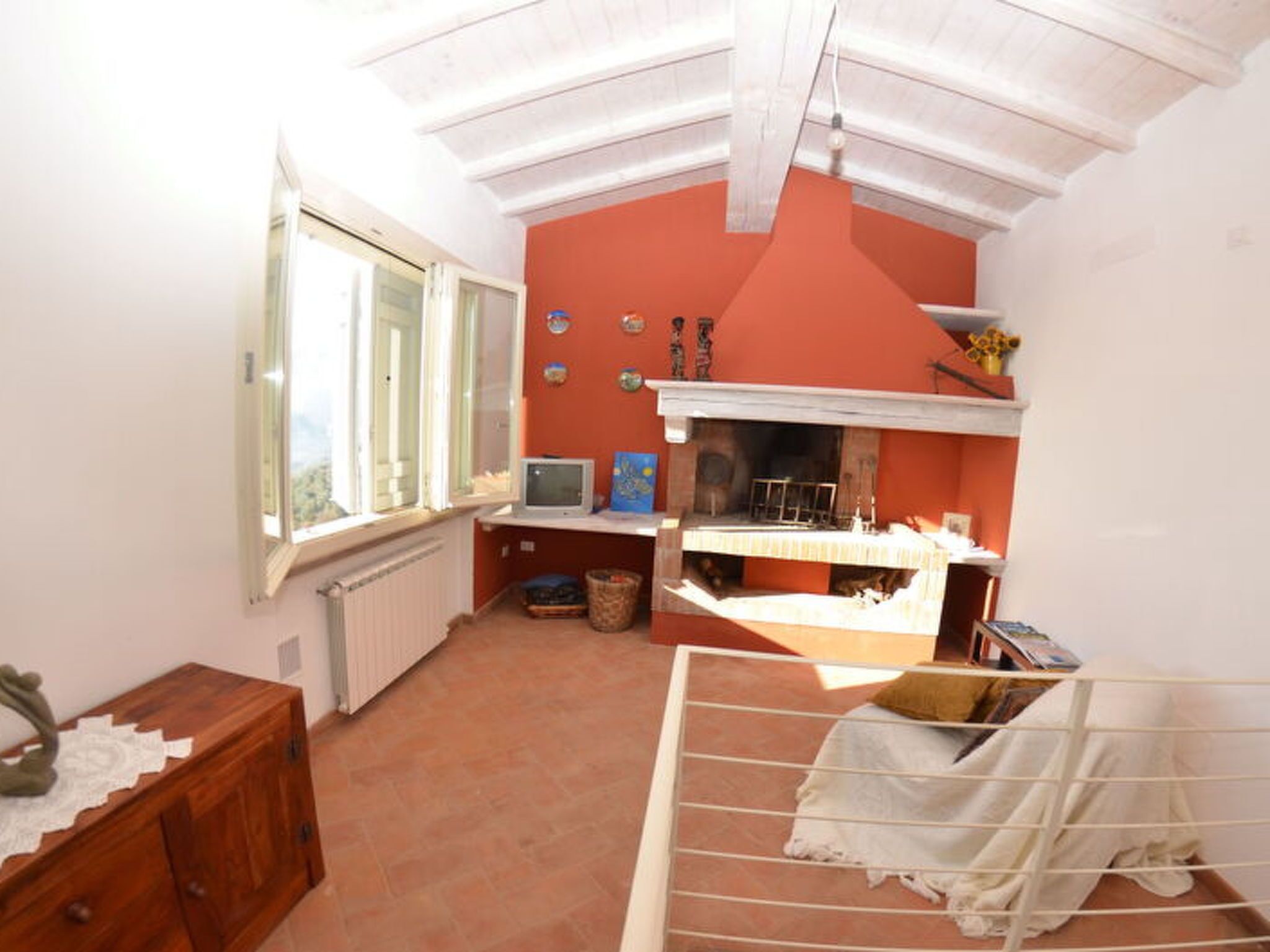 A room with a fireplace, a television, a window, and a wooden cabinet.