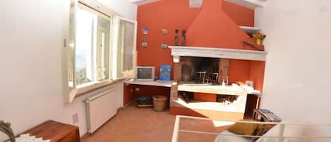 A room with a fireplace, a television, a window, and a wooden cabinet.