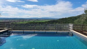 Una piscina rectangular con vistas a un paisaje lejano y una cerca.