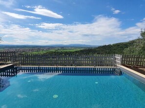 Ein rechteckiger Pool mit Blick auf eine entfernte Landschaft und einem Zaun.