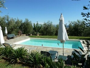 A rectangular swimming pool with a stone border, surrounded by lounge chairs and white umbrellas. - Le Case Di Carla Mela by Interhome (Borgo a Buggiano)