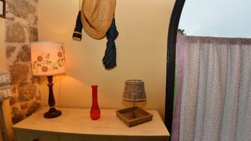 Une pièce comprenant un bureau, une lampe, un vase rouge, un panier tressé et un chapeau accroché au mur.