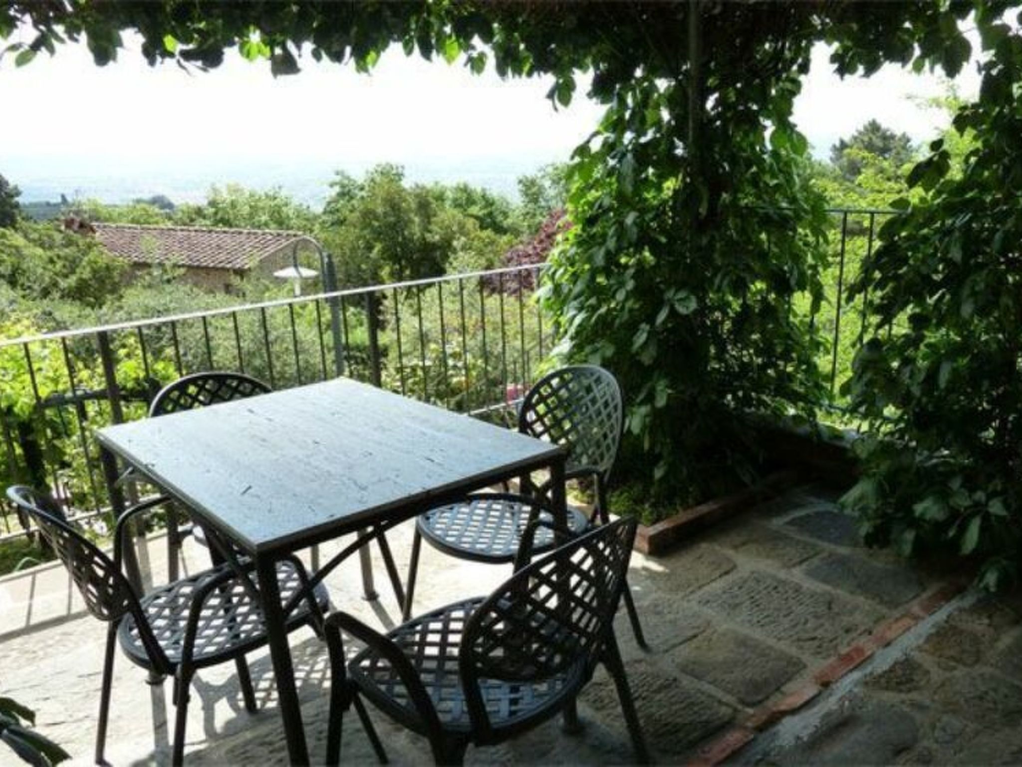 Un balcon agrémenté d’une table et de chaises, entouré de verdure et offrant une vue sur le paysage.