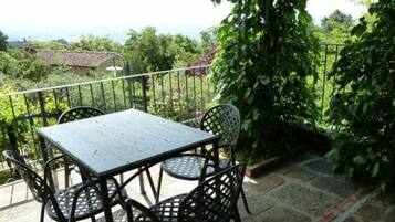 Un balcon agrémenté d’une table et de chaises, entouré de verdure et offrant une vue sur le paysage.