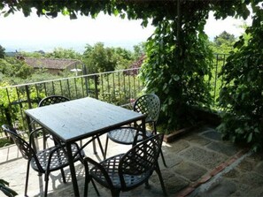 A balcony with a table and chairs, surrounded by greenery and a view of the landscape. - Le Case Di Carla Mela by Interhome (Borgo a Buggiano)