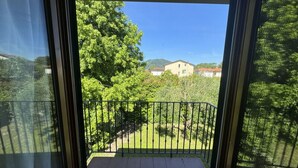 Ein Balkon mit Blick auf eine grüne Landschaft und Gebäude in der Ferne.