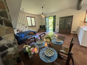 A dining area with a table set for four, a blue sofa, and a stone wall. - Dependance Egle by Interhome (Ciciana)