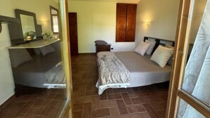 Ein Schlafzimmer mit Bett, Spiegel, Kleiderschrank und einem kleinen Nachttisch.