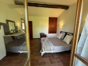 A bedroom with a bed, a mirror, a wardrobe, and a small bedside table. - Dependance Egle by Interhome (Ciciana)