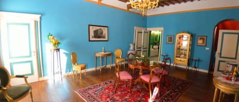 A room with a wooden ceiling, a chandelier, a dining table with chairs, a patterned rug, and a mirror.