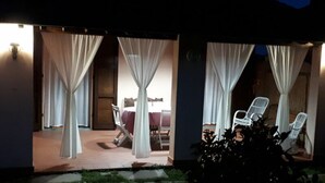 A covered outdoor area with a table and chairs, draped with white curtains, and a small garden area with greenery. - Al Vecchio Pozzo by Interhome (Buti)
