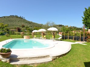 A swimming pool with a stone deck, surrounded by grass and a hill in the background. - Al Vecchio Pozzo by Interhome (Buti)