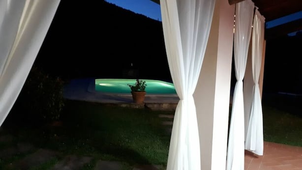 A covered outdoor area with white curtains, a potted plant, and a pool. - Al Vecchio Pozzo by Interhome (Buti)