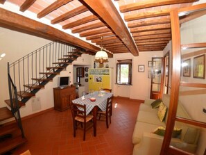 Ein Essbereich mit einer Holztreppe, einem Tisch mit Stühlen und einer Couch.