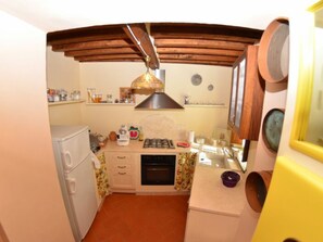 Une cuisine compacte équipée d’une cuisinière à gaz, d’un petit four, d’un réfrigérateur et d’un plafond en bois.