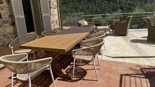 A terrace with a wooden table and wicker chairs, overlooking a mountainous landscape. - Casale Al Sasso by Interhome (Capannori)