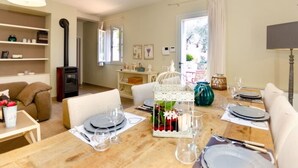 A dining area with a wooden table set for four, a white birdcage centerpiece, and a view of the outdoors through a window. - Casale Al Sasso by Interhome (Capannori)