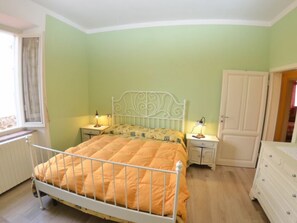 Ein Schlafzimmer mit einem Bett, Nachttischen, einem Kleiderschrank und einem Fenster.