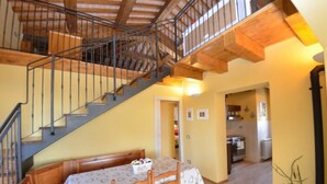 Un espace repas avec une table et des chaises, un escalier et une cuisine en arrière-plan.