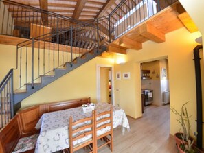Ein Essbereich mit Tisch und Stühlen, eine Treppe und eine Küche im Hintergrund.