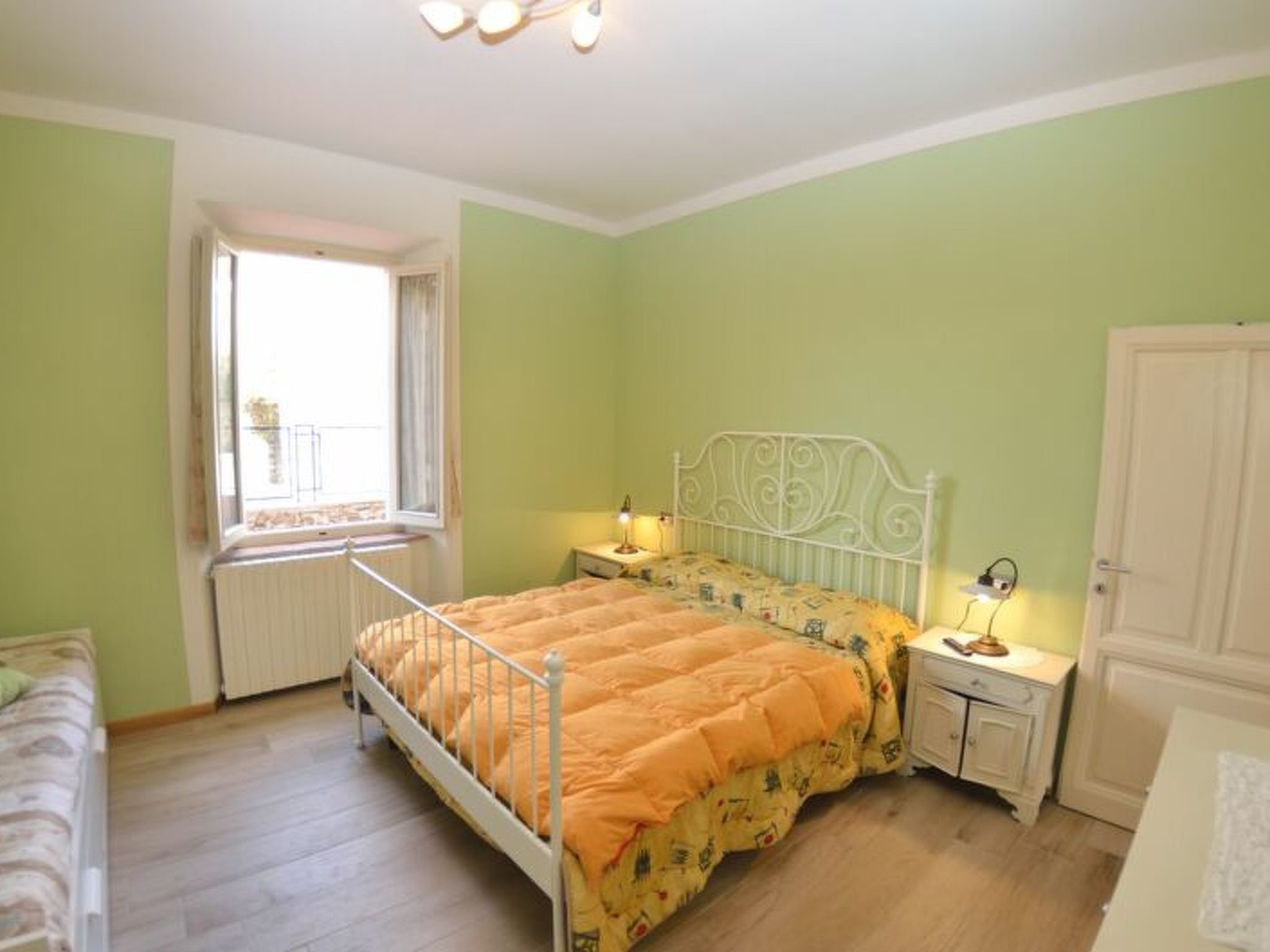 Une chambre à coucher avec un lit, des tables de chevet, une fenêtre et une porte.