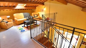 Une pièce de style « loft », avec un plafond en bois, un escalier et un ensemble de canapés.