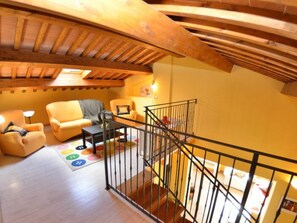 Ein Loft-Zimmer mit Holzbalkendecke, einer Wendeltreppe und einer Sofagarnitur.