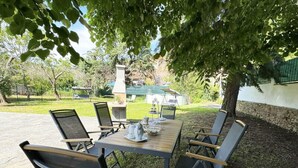An outdoor dining area with a table and chairs, surrounded by trees and a view of a building in the background. - Il Volo Del Nibbio by Interhome (Vecchiano)