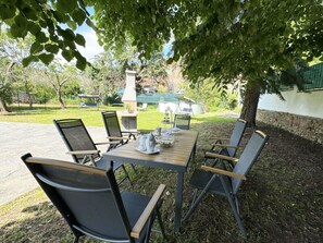 An outdoor dining area with a table and chairs, surrounded by trees and a view of a building in the background. - Il Volo Del Nibbio by Interhome (Vecchiano)