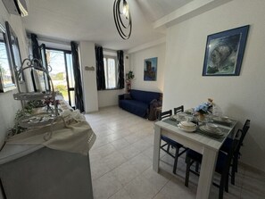 A dining area with a table set for four, a sofa in the background, and a dining table with chairs. - Il Volo Del Nibbio by Interhome (Vecchiano)