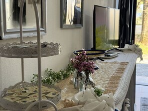 A table with a decorative tray, a vase with flowers, and a flat-screen TV. - Il Volo Del Nibbio by Interhome (Vecchiano)