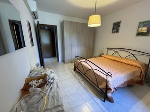 A bedroom with a bed, a mirror, a hanging light, and a door leading to another room. - Il Volo Del Nibbio by Interhome (Vecchiano)