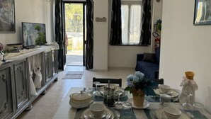 A dining area with a table set for four, a television on a cabinet, and a view through an open door. - Il Volo Del Nibbio by Interhome (Vecchiano)